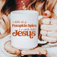 a woman holding a white coffee mug with the words pumpkin spice and jesus printed on it