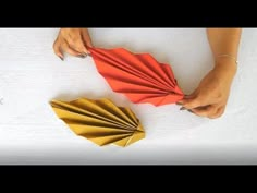 a woman is holding an origami fan next to a folded piece of paper