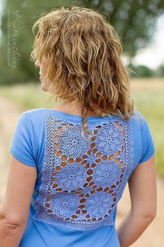 a woman in a blue shirt holding a white frisbee on a dirt road