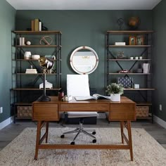 a home office with green walls and shelvings on the wall, along with a wooden desk topped with a white chair