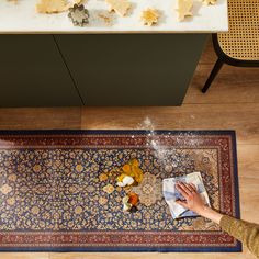 someone is cleaning the rug on the floor in front of their kitchen counter with various ingredients