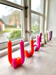 a row of colorful candles sitting on top of a window sill