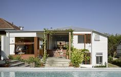 two people sitting at the back of a house next to a swimming pool