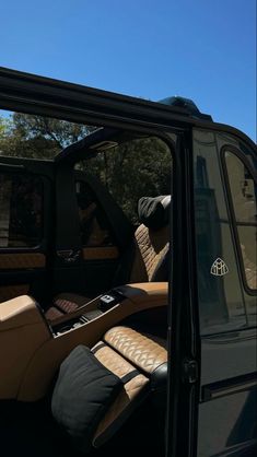 the interior of a vehicle with its door open and leather seats folded down in front of it