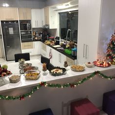 a kitchen filled with lots of food on top of a counter next to a christmas tree