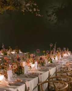 a long table is set up with flowers and candles for an outdoor wedding reception at night