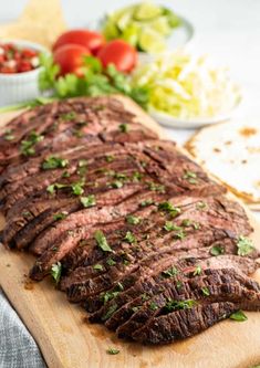 sliced flank steak on cutting board with salad and pita bread in the foreground