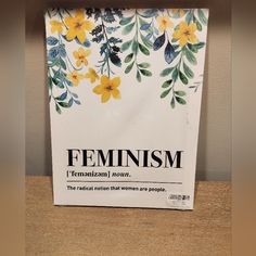 a paper bag with flowers on it sitting on a table next to a sign that says feminist