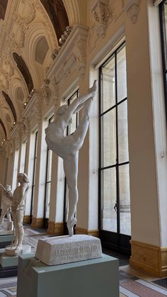 statues in the middle of a room with windows and doors on both sides, one is holding a woman's head