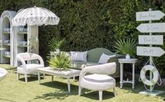 an outdoor seating area with chairs, tables and umbrellas on the grass in front of a wall