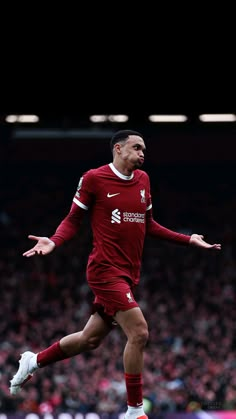 the soccer player is running with his arms out and eyes closed as he looks at the crowd