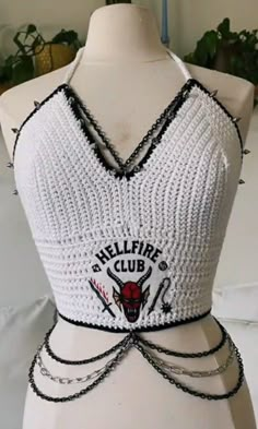 a mannequin wearing a white top with black chains around the neck and logo on it