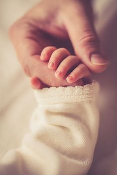 a baby's hand resting on its mother's leg