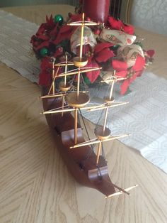 a wooden model ship sitting on top of a table next to a vase filled with flowers