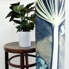 a potted plant sitting next to a tall vase on top of a wooden table