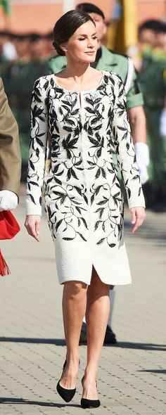 the woman is walking down the street wearing a dress with black and white flowers on it