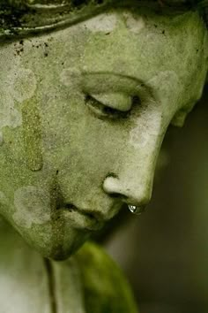 a close up of a statue with eyes closed and water dripping from her nose to her mouth