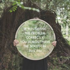 a person holding up a circular mirror with a quote on it in front of a tree