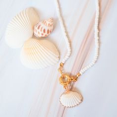 Elevate your beach style with our Kama'ole Seashell & Beads Necklace. Inspired by the rugged coastline of Maui, this bohemian island necklace features golden-trimmed ark seashells and smooth baby beads that add a touch of elegance to any outfit. The unique pendant shape and golden clasp make it easy to wear and perfect for any occasion. Material: baby white beads & real ark seashell Pendant: ~ 1" W x 1" L Length: ~ 15" Gold lobster claw adjustable fastener Jewelry is sold as all sales final - no return Gold Shell Necklace With Starfish Charm For Beach, White Shell Necklace With Pearl Charm For Vacation, White Beaded Shell, Beach Shell-shaped Charm Necklaces With Pearl, Bohemian Starfish Charm Necklace For Beach, Shell-shaped Pearl Charm Necklaces For Beach, Shell-shaped Charm Necklaces With Pearl Charm For Beach, Bohemian Charm Necklaces With Starfish Charm For Beach, White Shell-shaped Shell Necklace