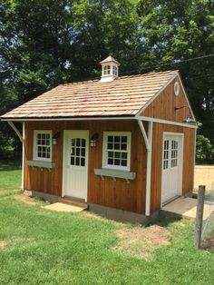 a small wooden shed sitting on top of a lush green field