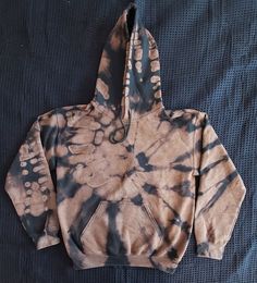 a brown and black tie - dyed hoodie on a bed