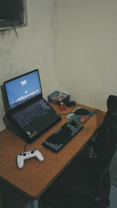 an open laptop computer sitting on top of a wooden desk next to a game controller