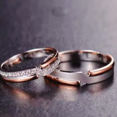 two wedding rings sitting on top of a black table next to each other with diamonds in them