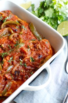 a casserole dish with onions, peppers and cilantro on the side