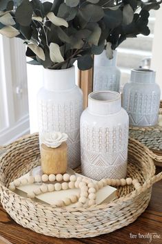 two white vases sitting on top of a table next to a wooden bead necklace