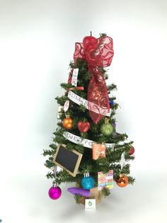 a small christmas tree decorated with ornaments and ribbons is on display against a white background