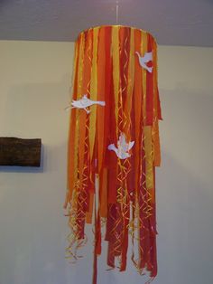 an orange chandelier hanging from the ceiling with birds on it and streamers