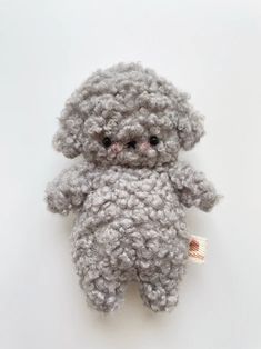 a gray teddy bear sitting on top of a white table