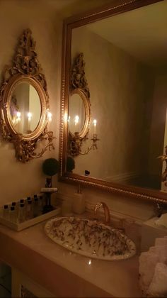 a bathroom sink under a large mirror next to a vanity with lights on the wall