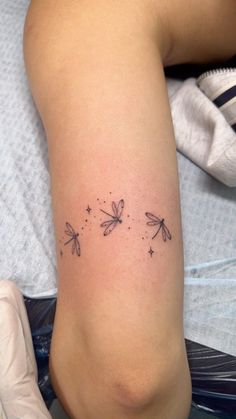 a woman's leg with three dragonflies on it and stars in the sky