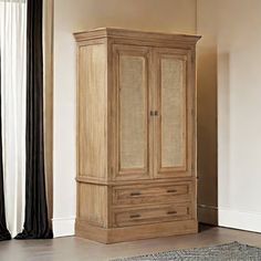 a tall wooden cabinet sitting in the middle of a living room next to a window