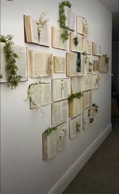 several books are hung on the wall with plants growing out of them and attached to it