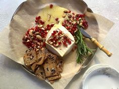 a plate with crackers, cheese and pomegranates on it