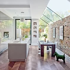 an open kitchen and dining room with brick walls, hardwood floors, and large windows