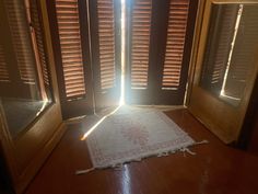 the sun shines through wooden shutters into a room with a rug on the floor