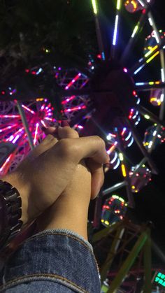 a person standing in front of a ferris wheel with their hand up to the camera