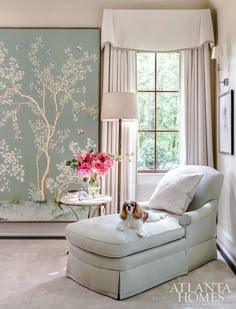 a dog is sitting on a chaise in front of a wall with a tree mural