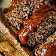 meatloaf and french fries are sitting on a plate with ketchup sauce