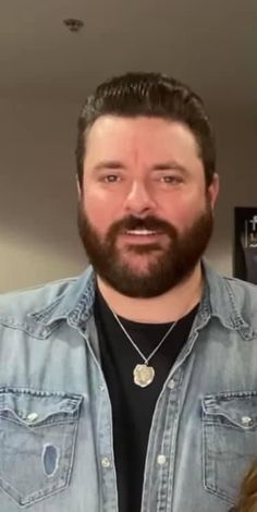 a man with a beard wearing a denim shirt