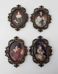 three framed portraits of women in ornate frames on a white wall, with one woman holding a baby