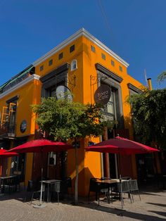 an orange building with tables and umbrellas outside