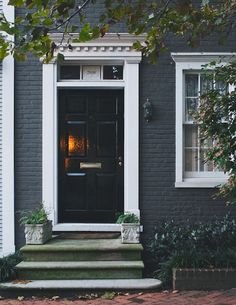 an image of a black door on a gray house with the words trend for 2017 painted brick