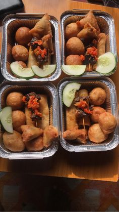 four trays filled with food on top of a wooden table