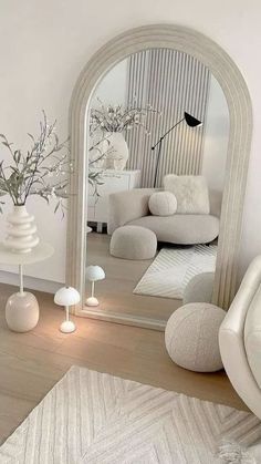 a living room with white furniture and a large mirror