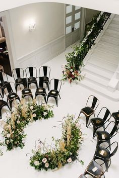 an arrangement of black chairs with flowers and greenery arranged in the shape of a heart