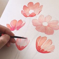 a person is drawing flowers with watercolors on paper